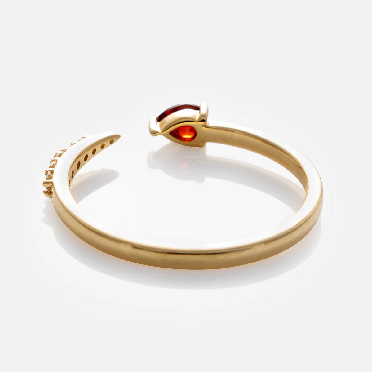 The Solid Gold Garnet and Sapphire Open Front Band is a 9k yellow gold ring with an open band, showcasing a marquise-cut garnet on one end and small engraved symbols on the other, presented on a white background.
