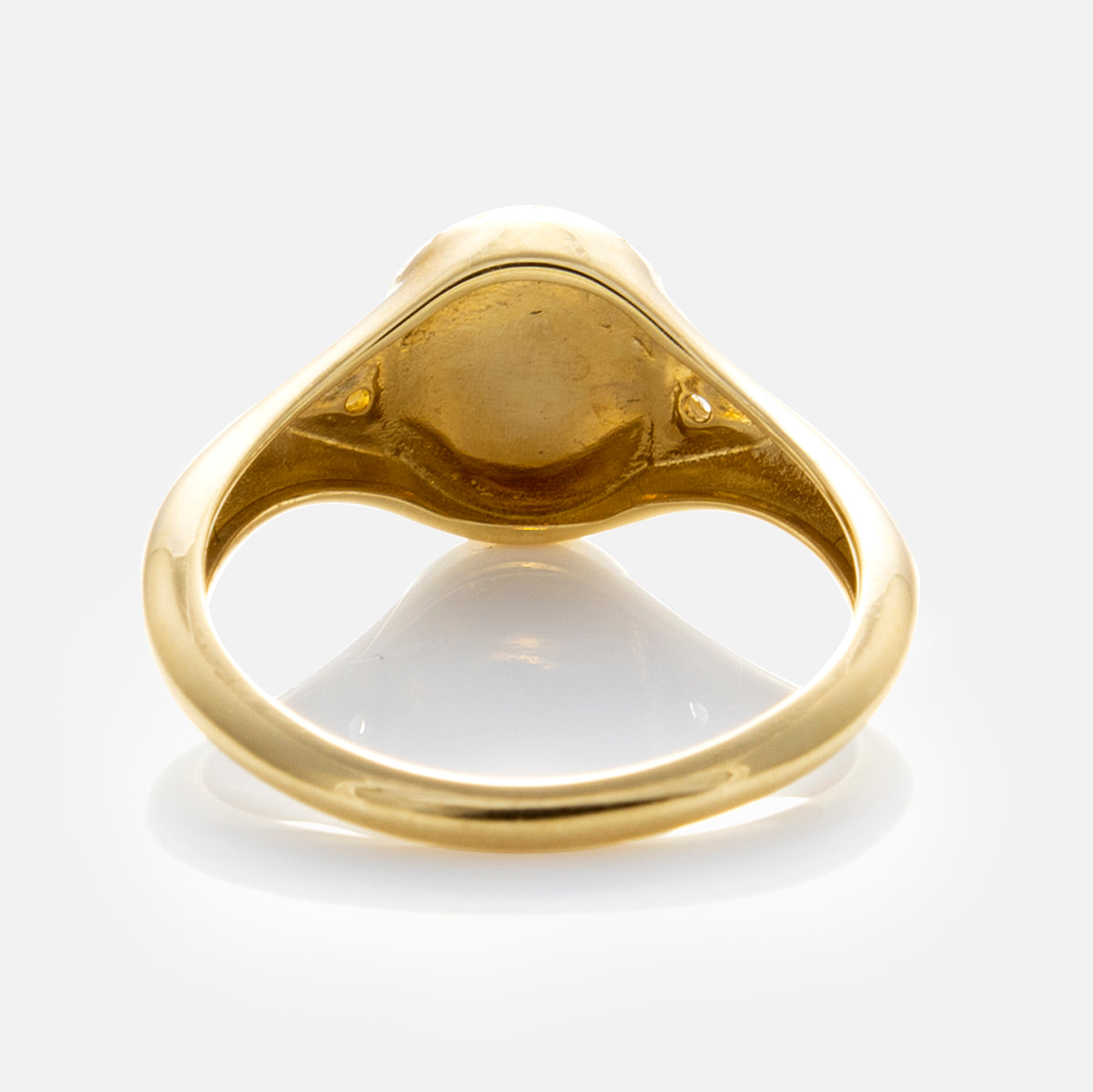 A close-up of the Solid Gold White Topaz Etched Signet Pinky Ring’s underside highlights its smooth, polished finish and sturdy build, set against a white background.