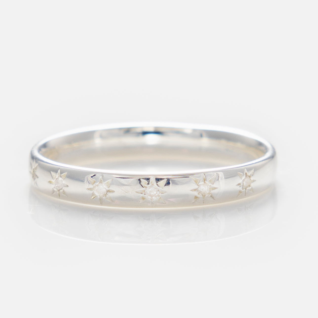 Introducing the Simple Star Set Diamond Band: a thin silver pinky ring adorned with engraved, evenly spaced eight-pointed stars around the band, shown on a plain white background.