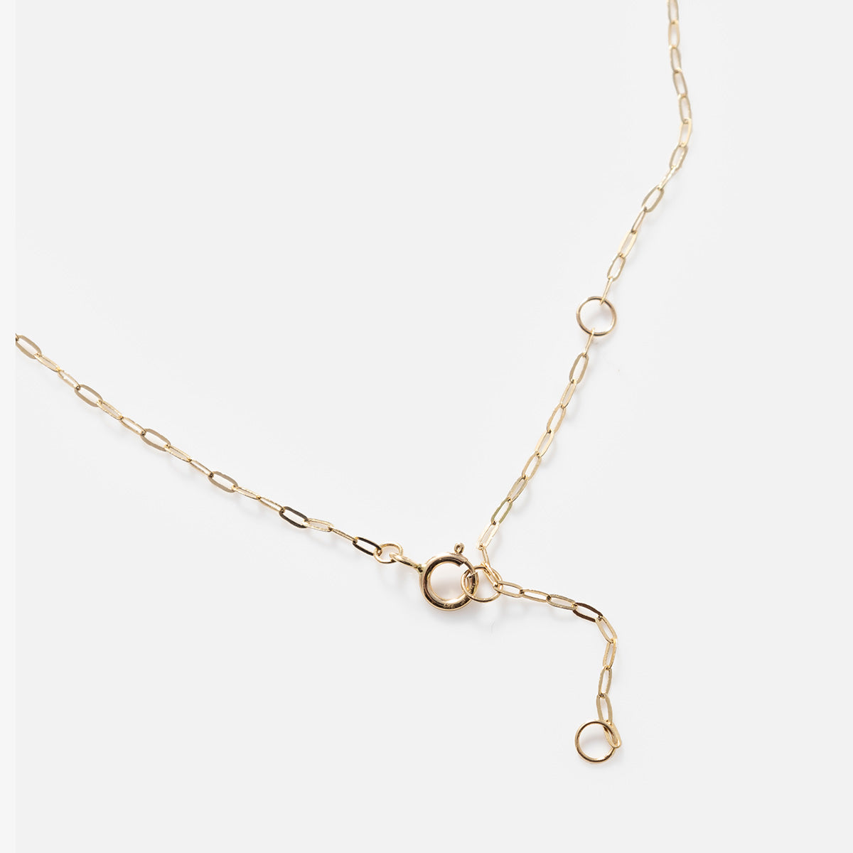 The Solid Gold Delicate Paperclip Chain features elongated links, a round spring ring clasp, and multiple attachment loops for adjustable length—perfect for necklace stacking. Shown unclasped on a plain white background.