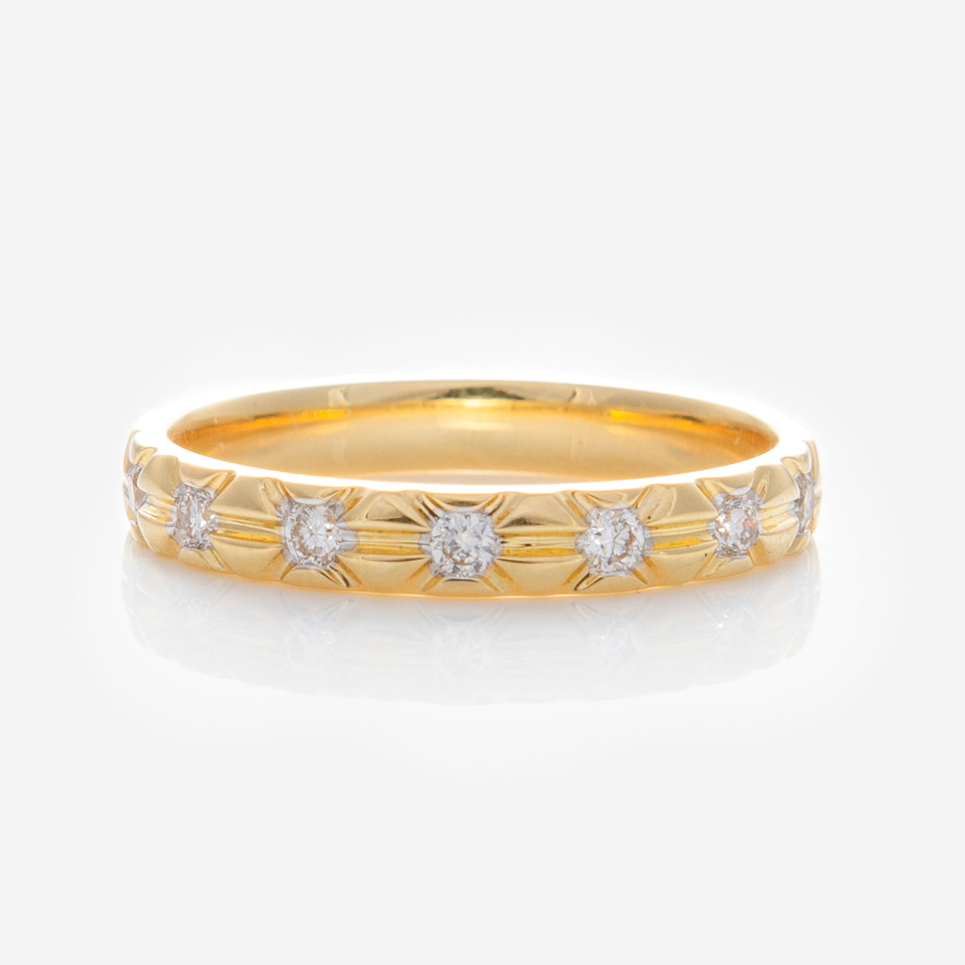 The Solid Gold Vintage Inspired Diamond Band features six lab-grown diamonds in star-shaped engravings around the band, displayed on a reflective white surface.