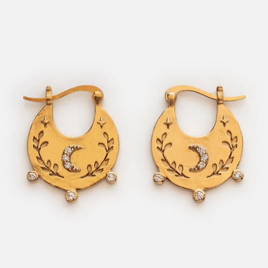 Celestial Bohemian Hoop Earrings in yellow gold feature crescent-shaped hoops engraved with leaves, stars, and a moon, accented by three round gemstones at the base and a sparkling crescent centerpiece.