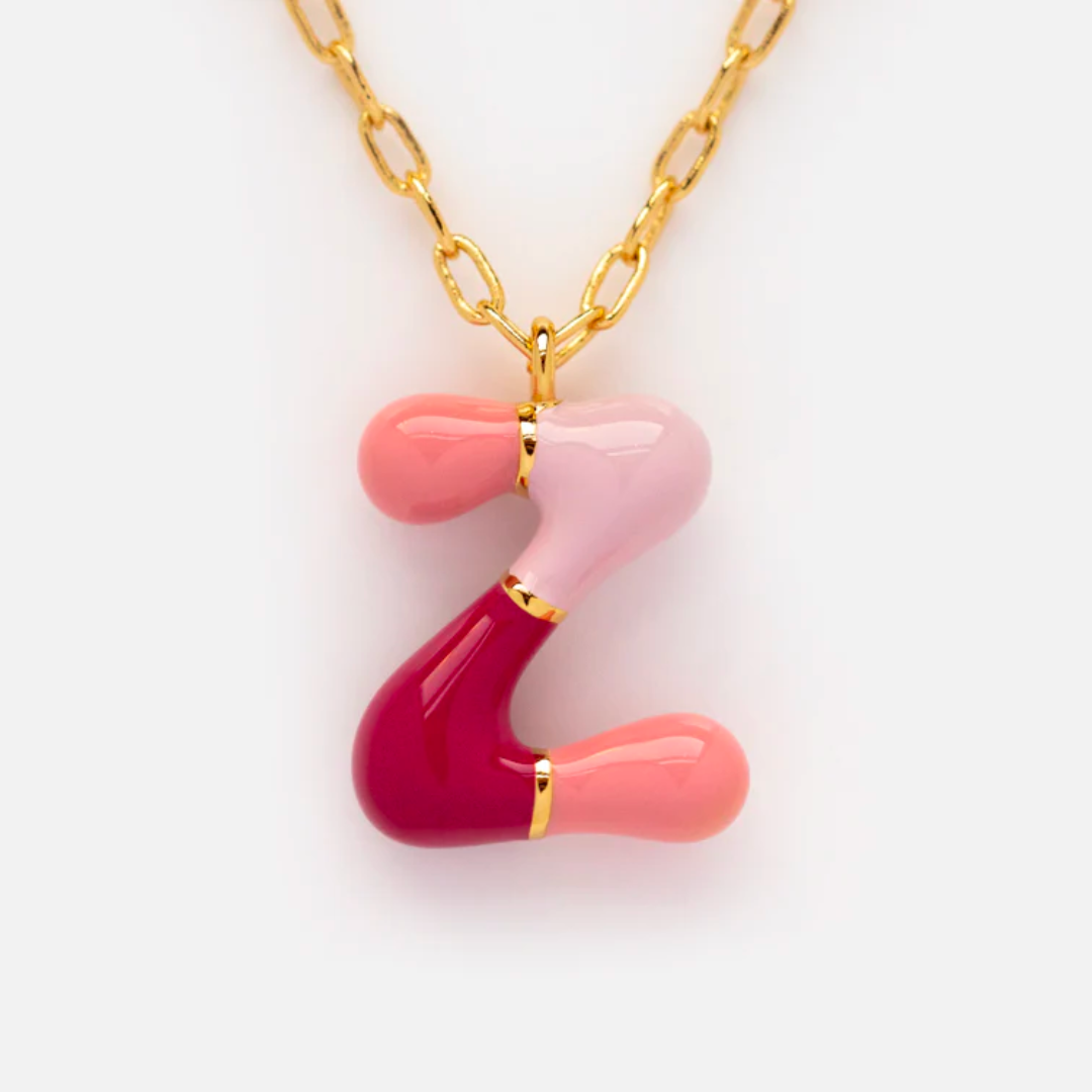 The Bubble Letter Necklace is a 14k gold plated piece with a Z-shaped pendant, highlighted by glossy red, pink, and peach sections divided by gold bands—a playful and colorful letters necklace.