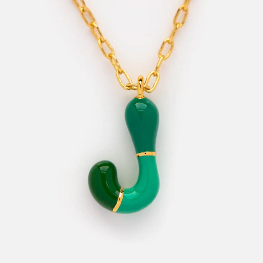 The Bubble Letter Necklace is a 14k gold plated piece with a gold chain and a curved J pendant in dark and light green, accented by small gold bands—a playful update to the classic bubble letter necklace.