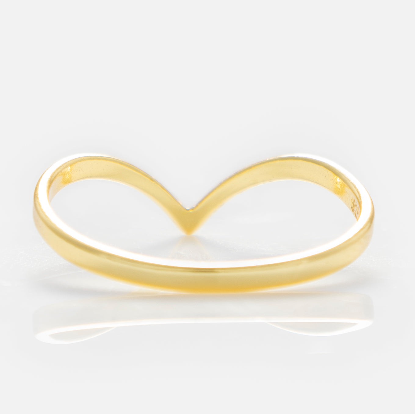 The Arch Ring is a delicate 18k yellow gold plated piece featuring a smooth band that forms a subtle V shape at the center, ideal for minimalist style or stacking, shown on a plain white background.