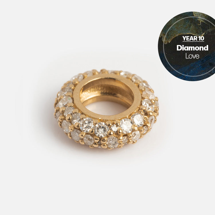 A round gold Solid Gold Anniversaire Charm, encrusted with small clear diamonds, is displayed on a white background. A circular label in the corner reads YEAR 10 Diamond Love—ideal for milestone jewelry or charm collections.