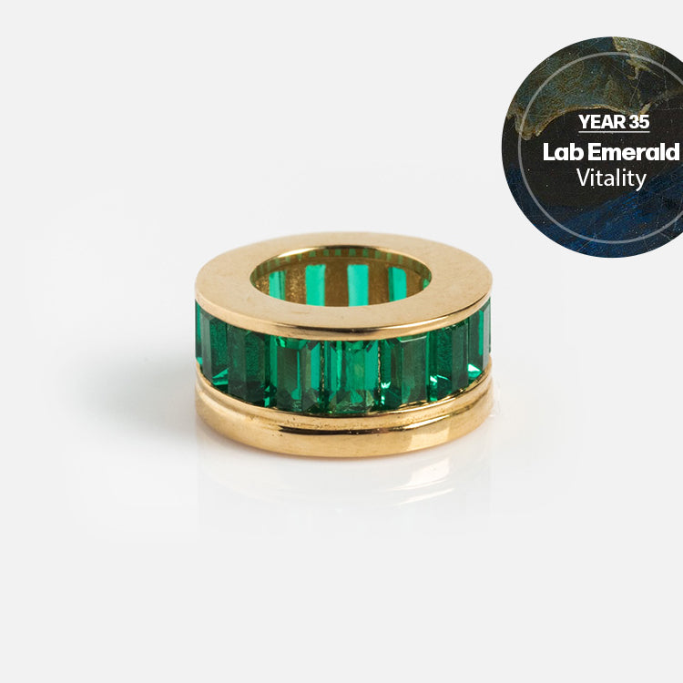 Solid Gold Anniversaire Charm shown on a white background, featuring vertical green rectangular stones. In the top right, a circular label reads Year 35 Lab Emerald Vitality—perfect milestone jewelry for your special celebration.