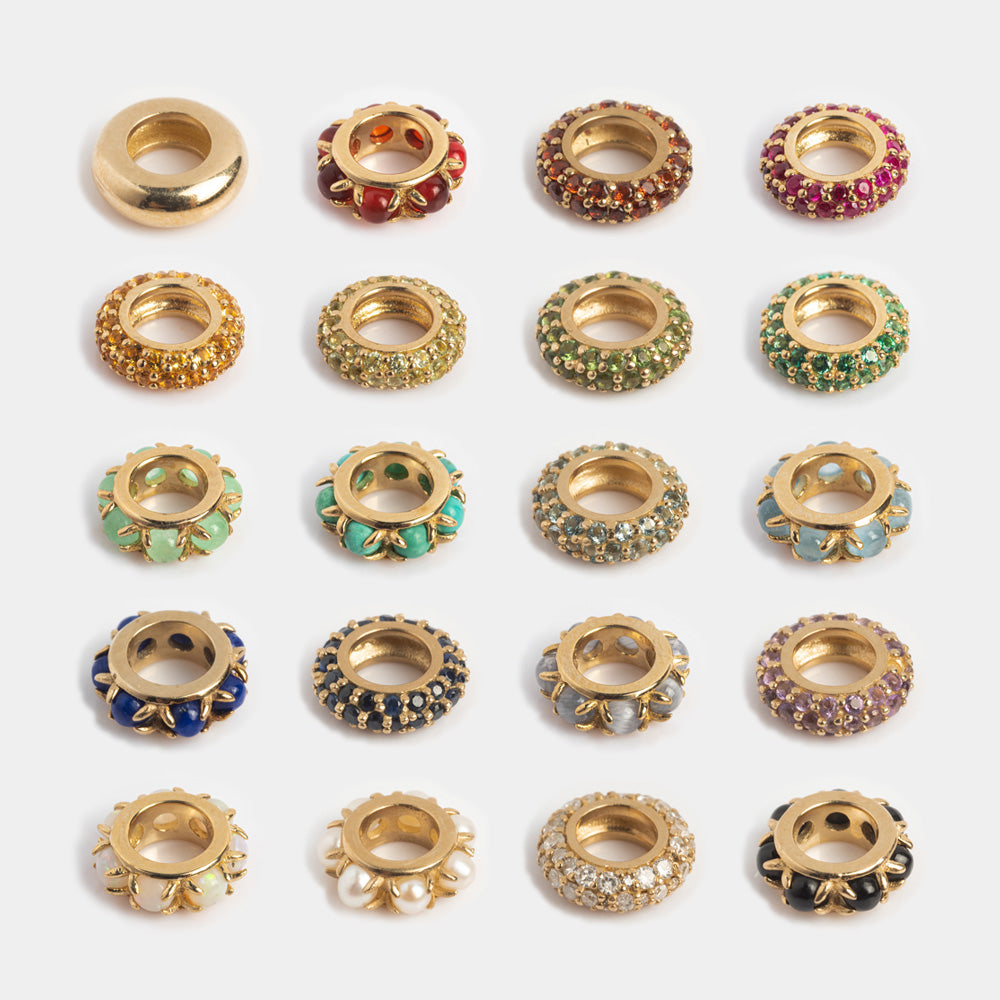 A set of 20 Solid Gold Anniversaire Charms, each with colorful gemstones or pearls, arranged in a grid on a white background—ideal for milestone jewelry or unique anniversary charms.