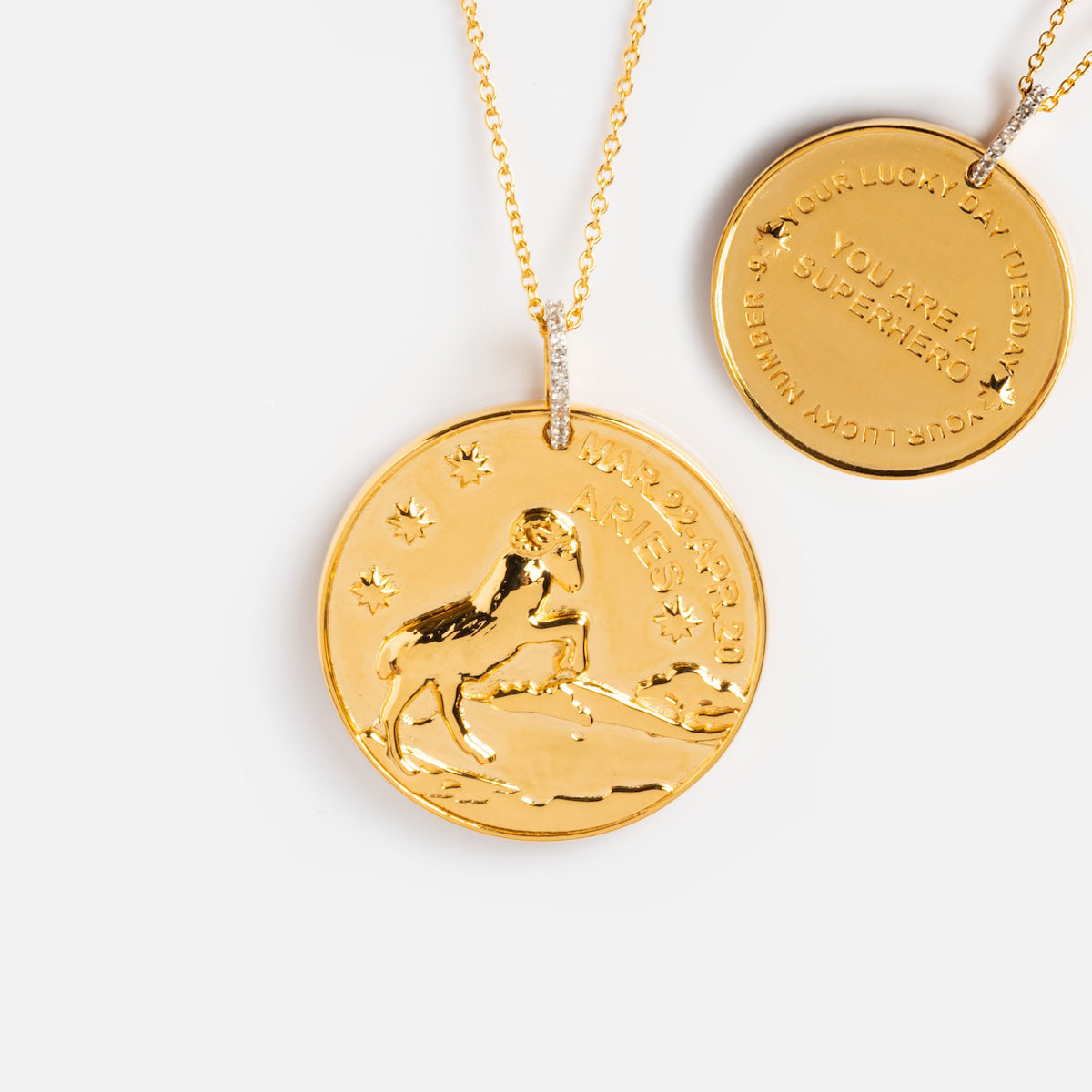 Two gold vermeil necklaces with round pendants: the Vintage Inspired Zodiac Coin Necklace shows an engraved ram, stars, and Aries, while the other features motivational text and Aries dates.