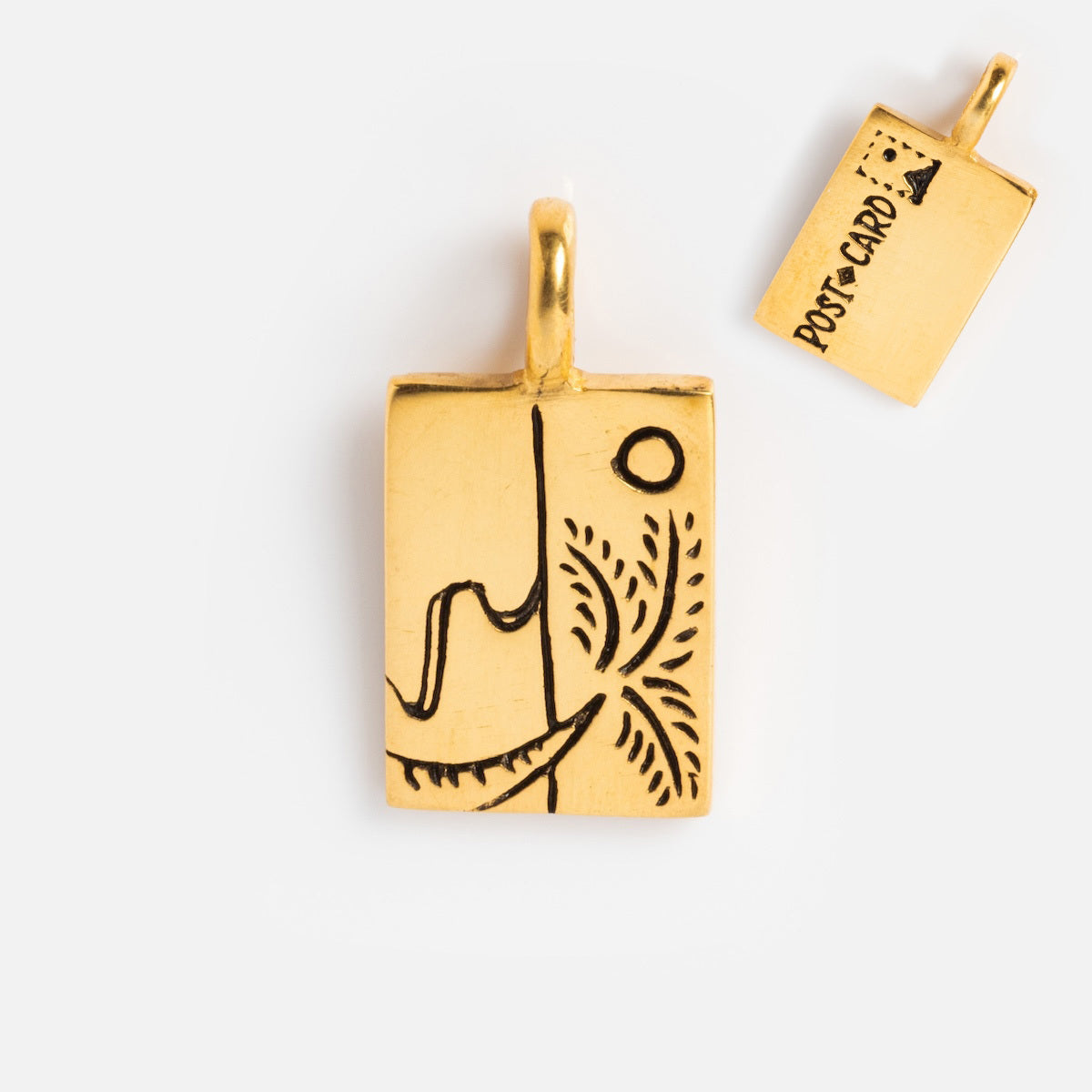 Charms by Hunt of Hounds: A gold vermeil rectangular pendant with a black abstract line and small circle on the front; the back features POSTCARD and a stamp illustration.
