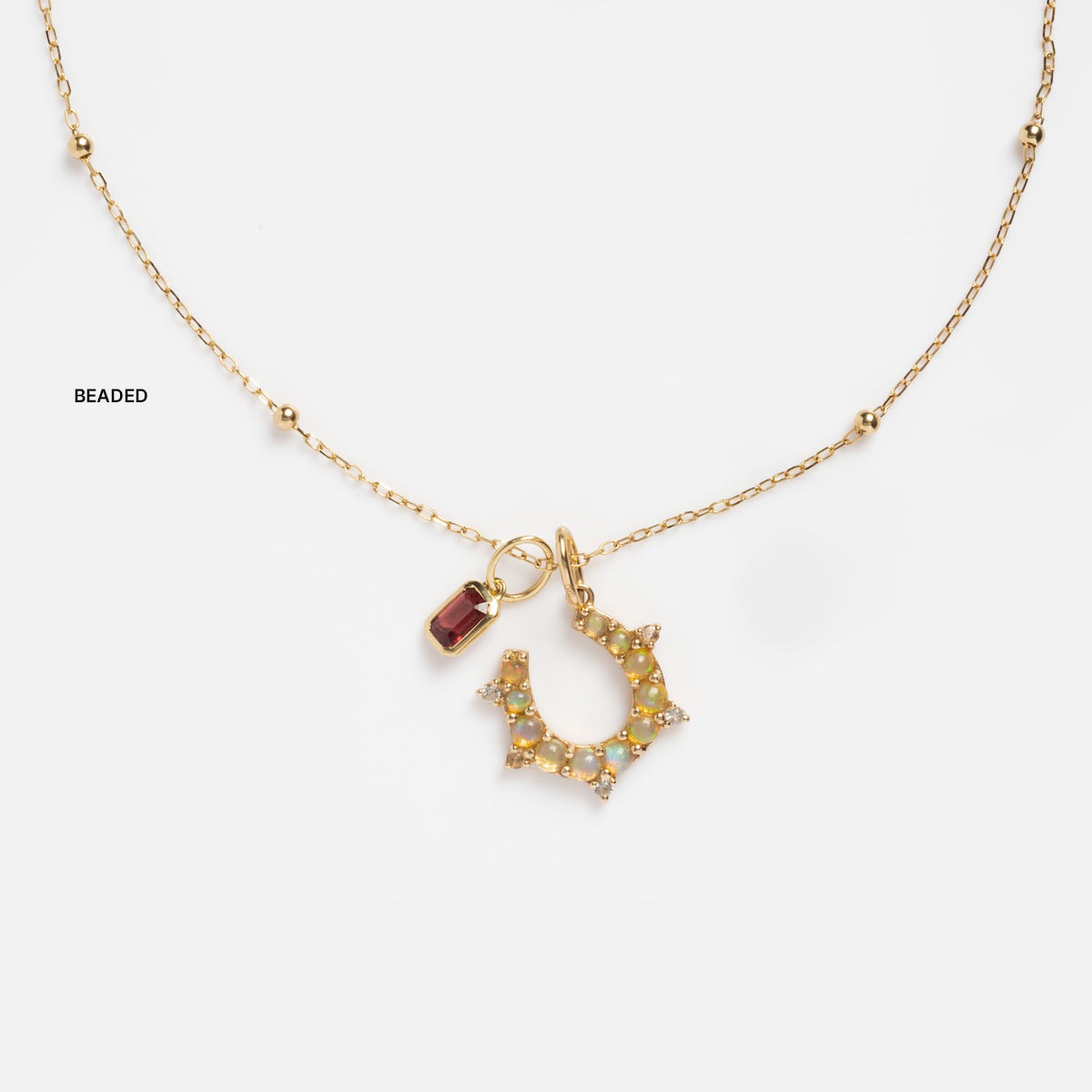 Solid Gold Chain for Charms shown on a white background, featuring delicate beading, a crown-shaped pendant with small gemstones, and a rectangular red gemstone charm.