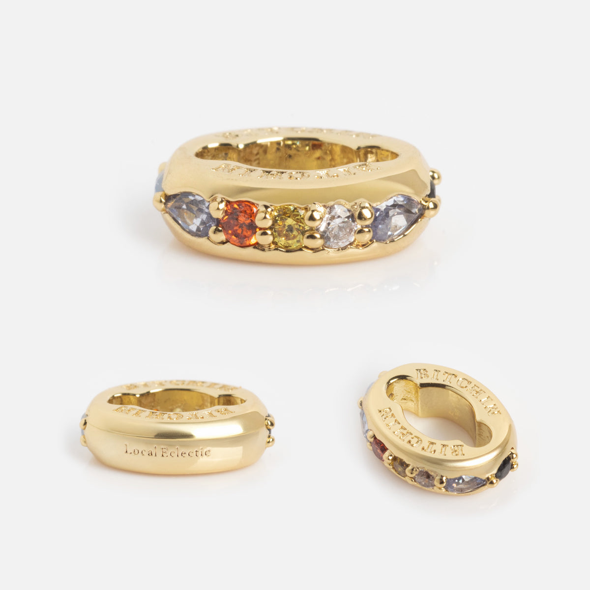 The Hidden Curse Word Spacer Charm is shown from various angles, highlighting its five colored gemstones set on top and the engraved text “Local Eclectic” and “KATE DAVIS” on the sides.