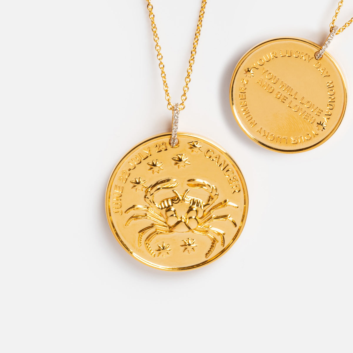 Two gold vermeil necklaces: a Vintage Inspired Zodiac Coin Necklace for Cancer with a crab and stars, and another vintage charm necklace inscribed with words of love and luck.