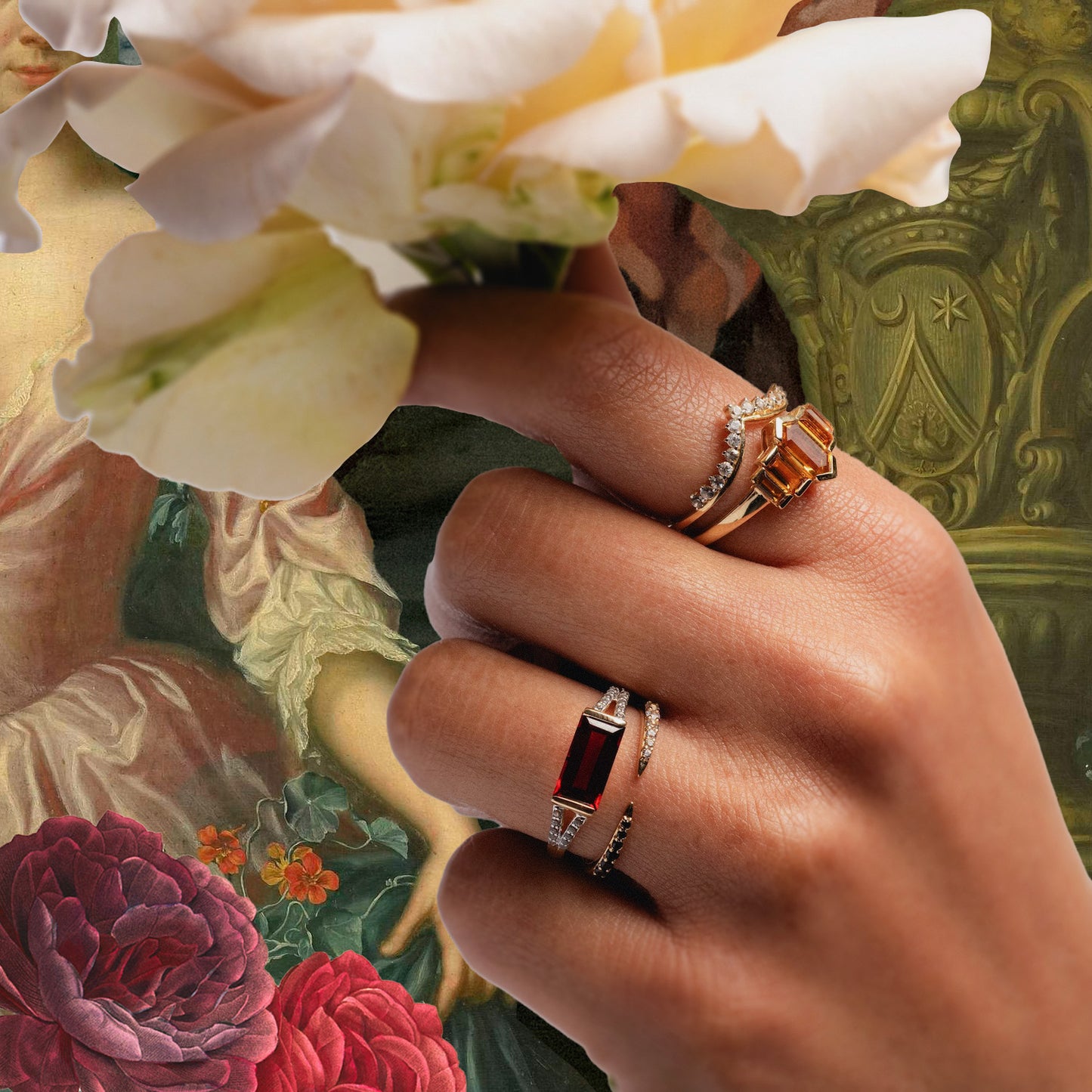 A hand holds a pale rose, adorned with the 14k Graduated Citrine Deco Ring and rings featuring red and orange gemstones, set against classical art with flowers and a figure in a green dress.