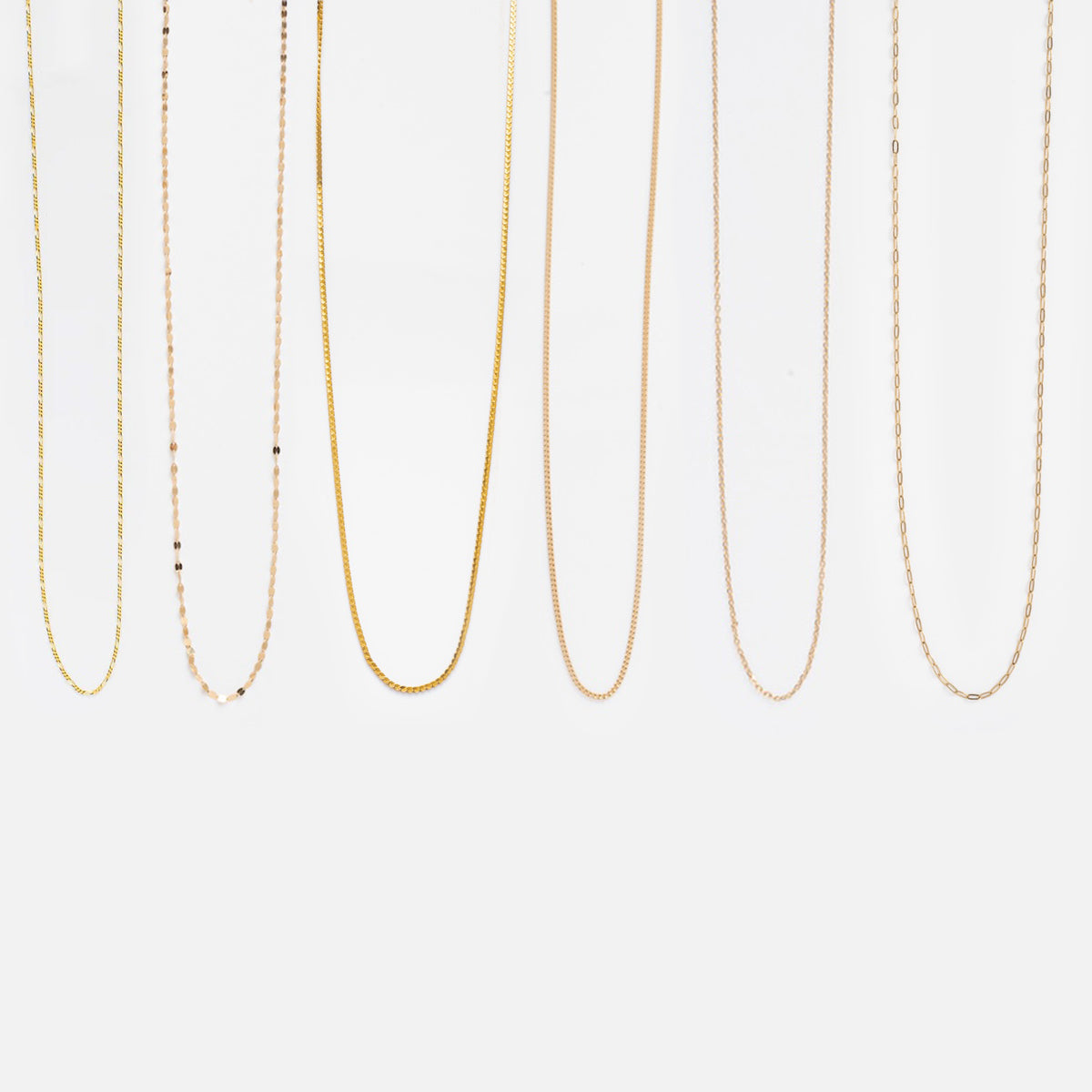 Six delicate Chain Add On gold necklaces in various styles hang vertically against a plain white background.