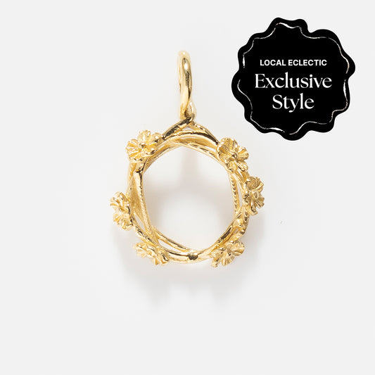 Charms by I Like It Here Club: Gold floral wreath pendant with intricate flower details and 12k yellow gold plating, displayed on white. A black seal in the corner marks it as a “Local Eclectic Exclusive Style,” adding personalized flair.