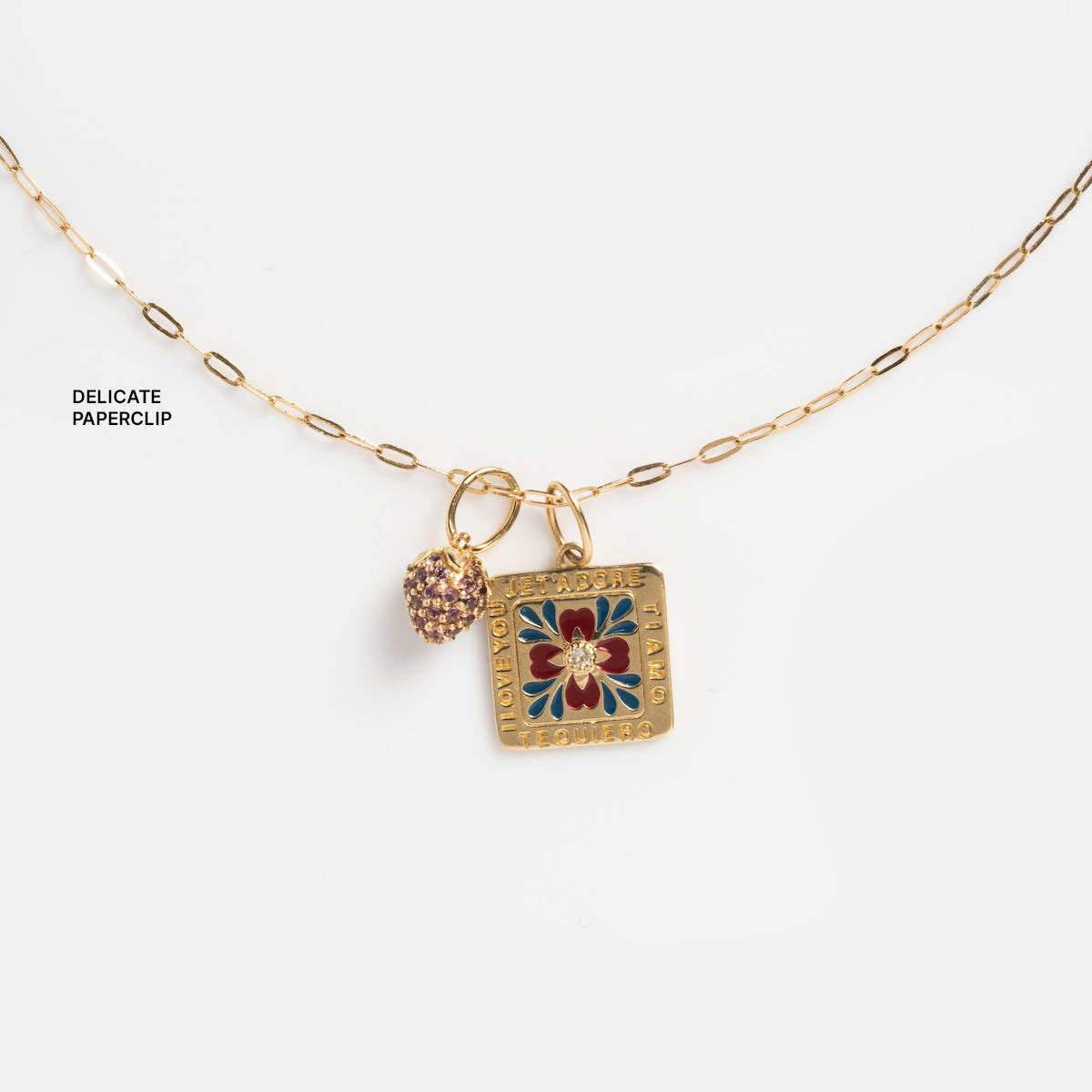 The Solid Gold Chain for Charms is a personalized necklace featuring a gold paperclip chain with two charms: a textured heart and a square charm showcasing a red and gold floral design with text around the edge.