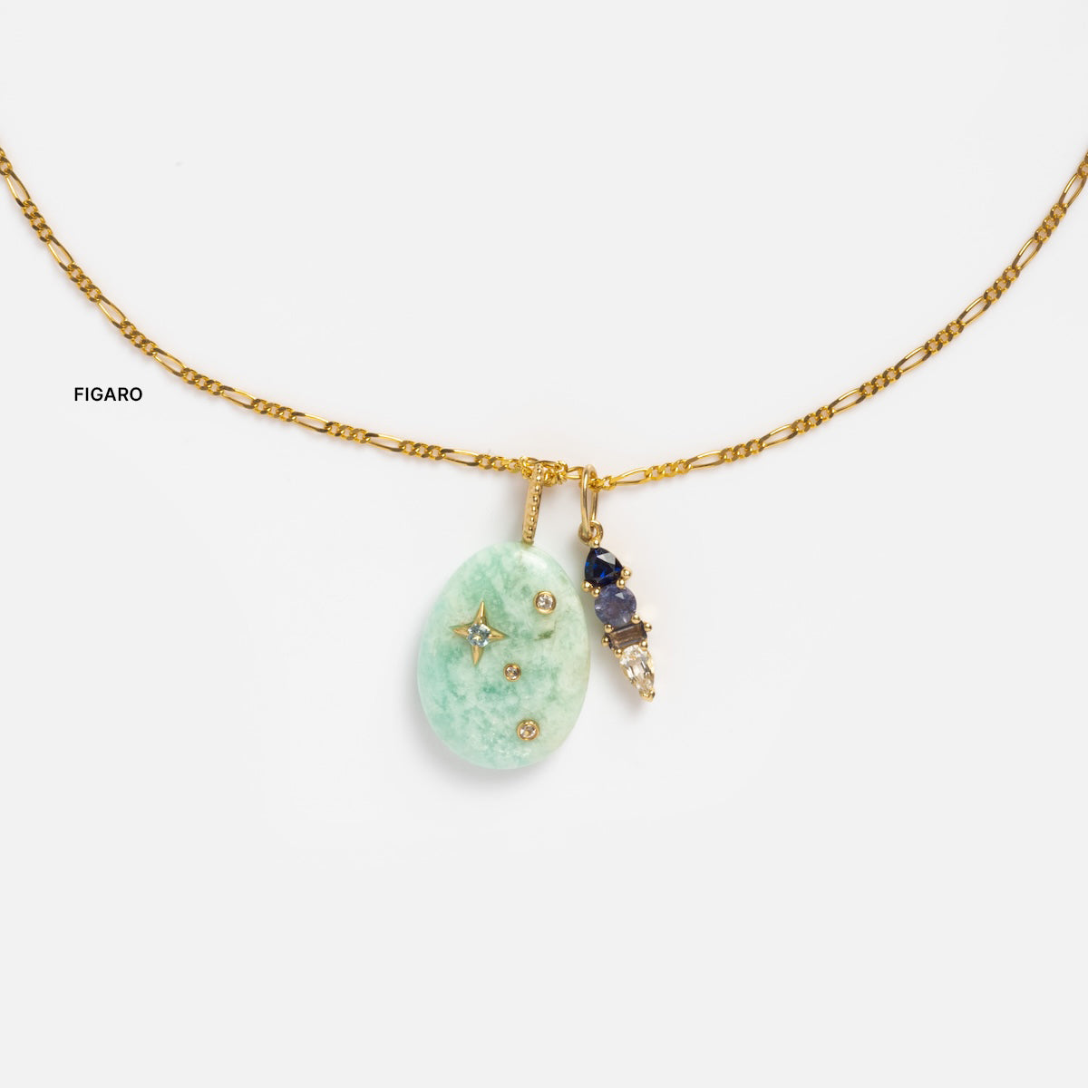A Solid Gold Chain for Charms, featuring a pale green oval pendant with small embedded gems and a star motif, paired with a cluster of blue and white stones.