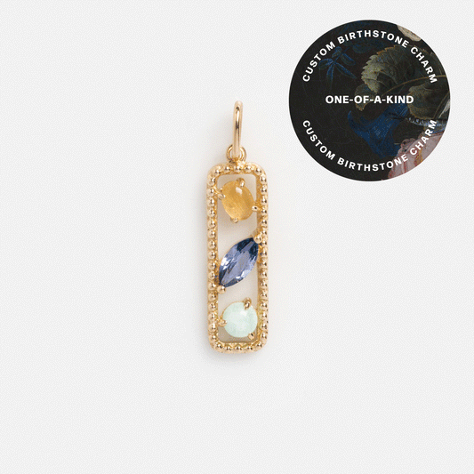 The Customizable Floating Birthstone Charm features a rectangular gold design with three vertical gemstones—yellow, blue, and light green. A circular corner label reads: Unique custom birthstone jewelry, one-of-a-kind.
