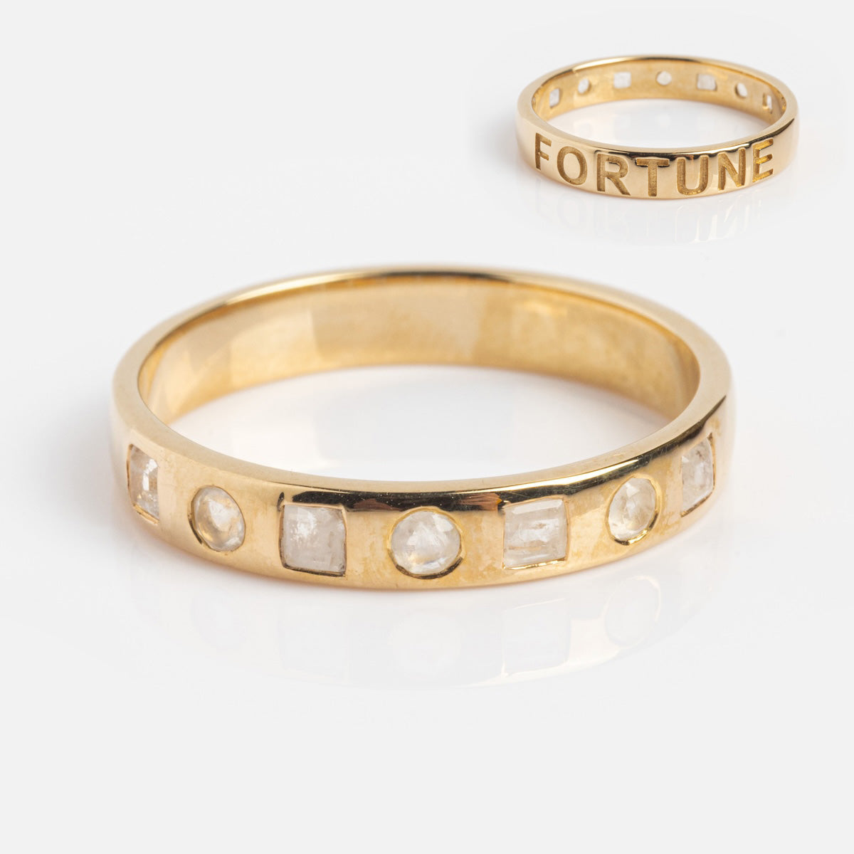 A 9k solid yellow gold ring, the Solid Gold Within You Birthstone Band (sample size 7), features inset clear natural stones around the band and is shown on a white background.