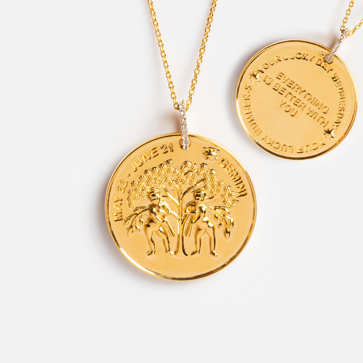 The Vintage Inspired Zodiac Coin Necklace features gold vermeil pendants with Gemini dates and two figures under a tree on the front; the back reads, “YOUR LUCKY TWINSMENA, DO EVERYTHING BETTER WITH YOU.”.