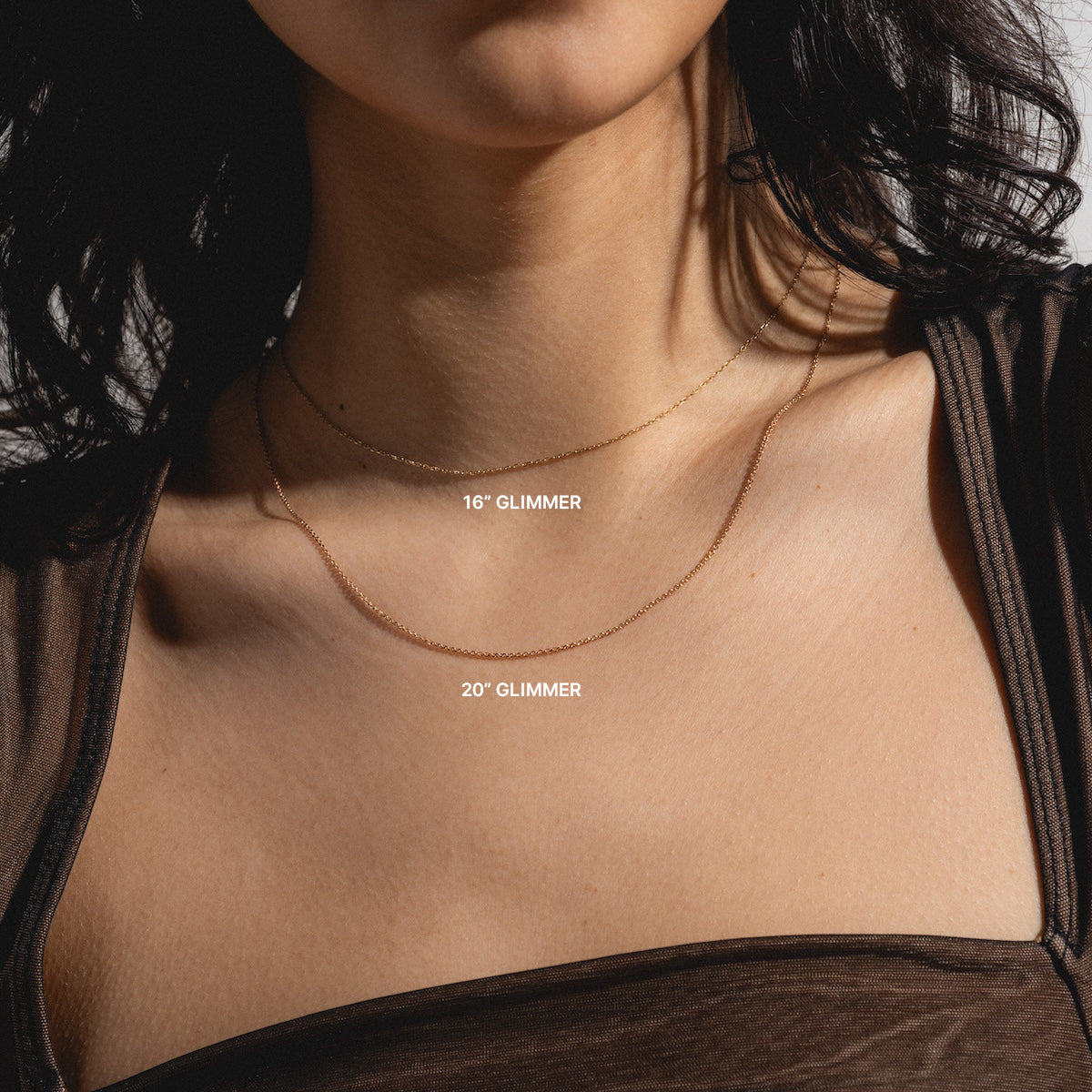 A woman in a sheer brown top models two Solid Gold Chain for Charms necklaces: a 16-inch chain at her neckline and a 20-inch chain hanging lower, each labeled with its length.
