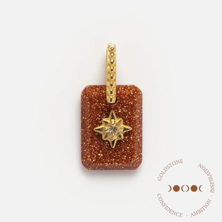 The Solid Gold Crystal Amulet Charm for Manifestation is a rectangular goldstone pendant with a sparkling brown surface, gold star centerpiece, and dotted gold bail, designed to inspire confidence, ambition, and inspiration.