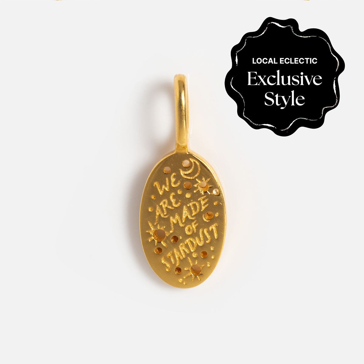 The Charms by Hunt of Hounds gold vermeil oval pendant features engraved stars, dots, a crescent moon, and “We are made of stardust.” A black badge notes its a Local Eclectic Exclusive Style.