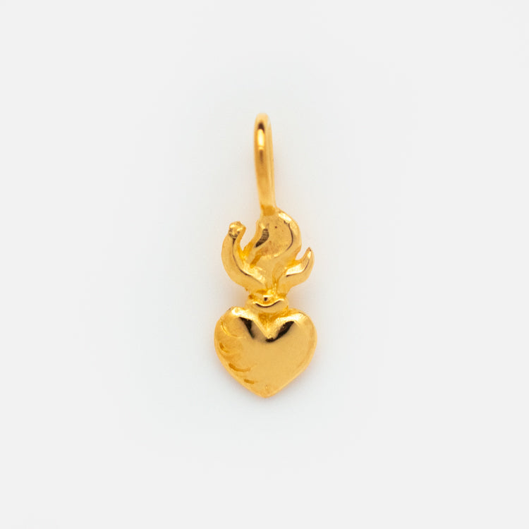 The Charms by Hunt of Hounds is a small gold vermeil pendant featuring a shiny heart with a stylized flame design at the top, displayed on a plain white background.