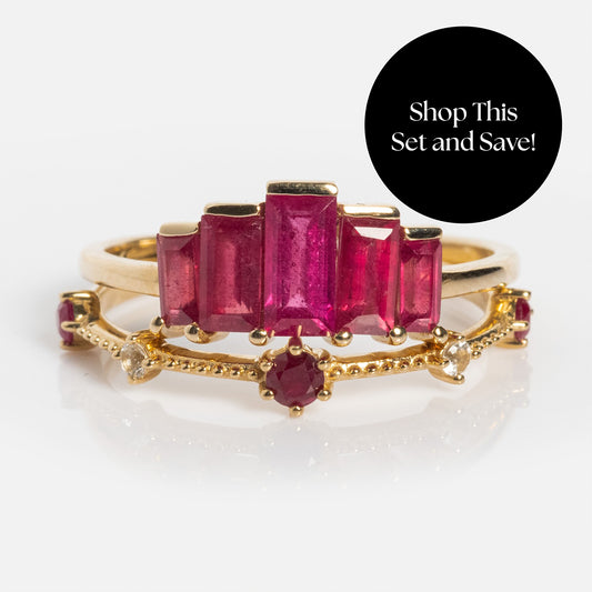 The Solid Gold 2025 July Capsule Ruby Ring Set features baguette-cut rubies and diamonds, stacked for a stunning birthstone look. A black circle overlay reads, Shop This Set and Save! on a white background. Includes free gift.