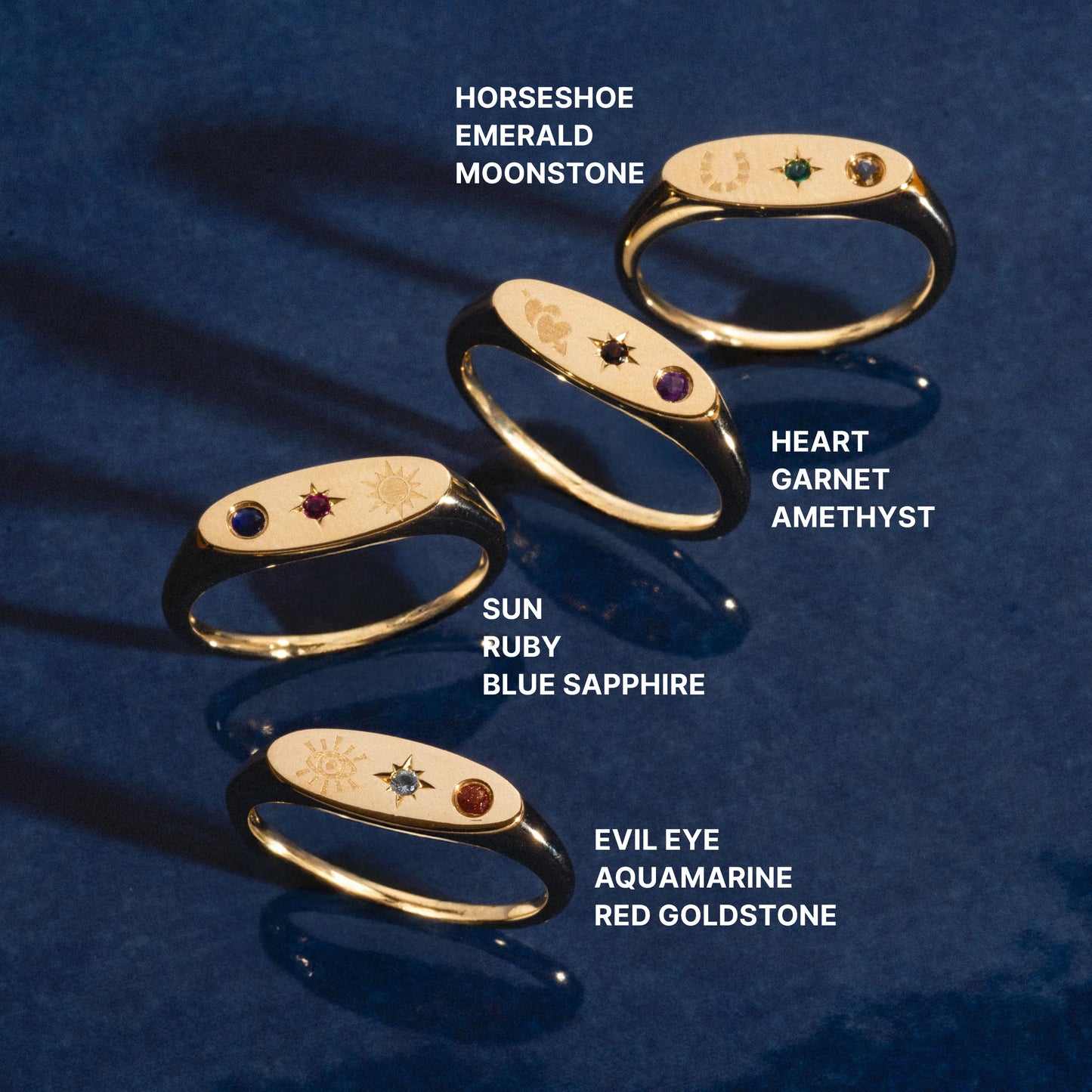 Set of gold manifestation rings with gemstones on a blue background
