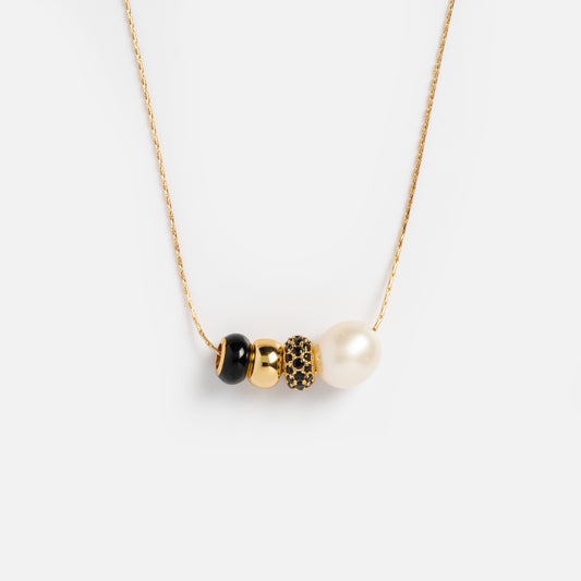 The Isla Bead Necklace features a delicate 14k gold plated chain with four beads—a black bead, gold bead, black bead with gold accents, and freshwater pearl—displayed on a plain white background.