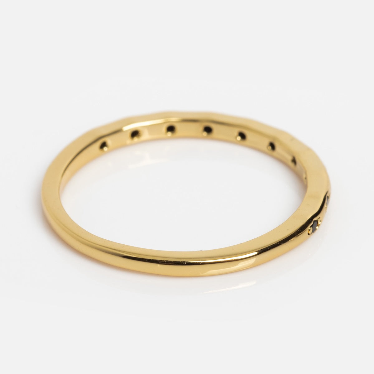 The Regency Stacking Ring features a thin yellow gold plated band with a smooth, slightly wavy surface and small round holes along one side, shown on a white background.