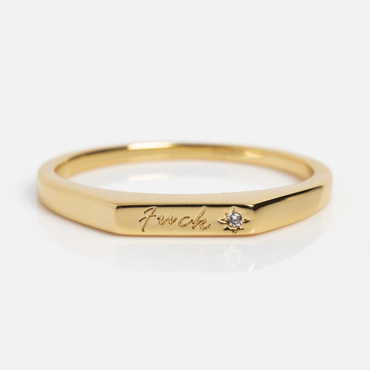 The Tiny Fuck Bold Stacking Ring Set features 14k gold plating, Touch engraved in cursive, and a small diamond accent beside the inscription, shown on a white background.
