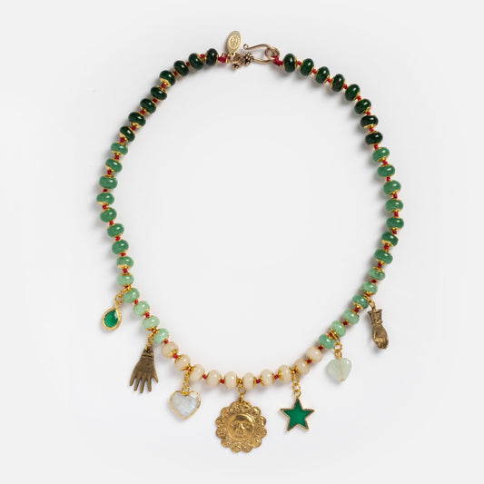 The Zodiac Daydream Necklace showcases green, gold, and cream jade beads with six dangling gold and gemstone charms—a hand, heart, sun face, star, and teardrop—arranged on a white background.