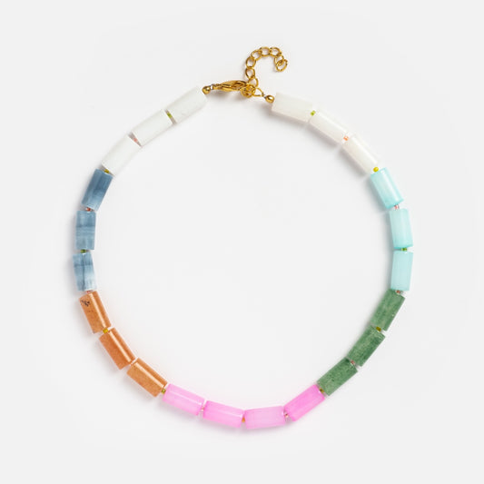 The Beaded Gemstone Tube Necklace showcases rectangular pastel beads in white, blue, pink, green, and gold with an adjustable 18k gold-plated clasp, displayed on a white background.