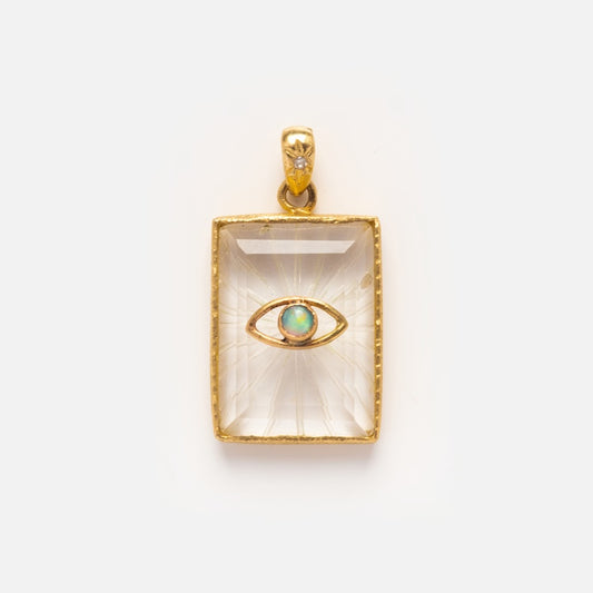 The Opal Eye Amulet for Protection is a rectangular gold necklace pendant starring a blue-green opal iris and diamond-accented bail, with a clear gemstone center and opal eye design, shown against a plain white background.