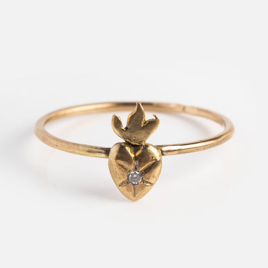 The Amulet Sacred Heart Ring is crafted in 14k solid yellow gold, featuring a heart-shaped design with a central diamond and a sculpted flame detail, shown on a plain white background.