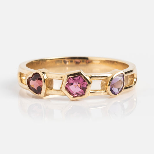 The Mixed Shape Stones Open Band Ring features a thick gold band with three striking gemstones: a round pink stone, a central hexagonal dark pink gem, and an oval light purple stone for bold statement style.