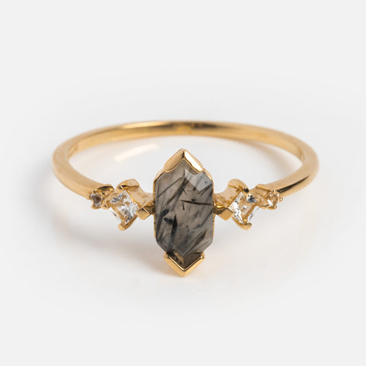 Exclusive to Local Eclectic, the Solid Gold Black Rutilated Quartz Hexagon Ring for Strength features a marquise-cut black rutilated quartz center, flanked by two square-cut clear stones on each side against a plain white background.