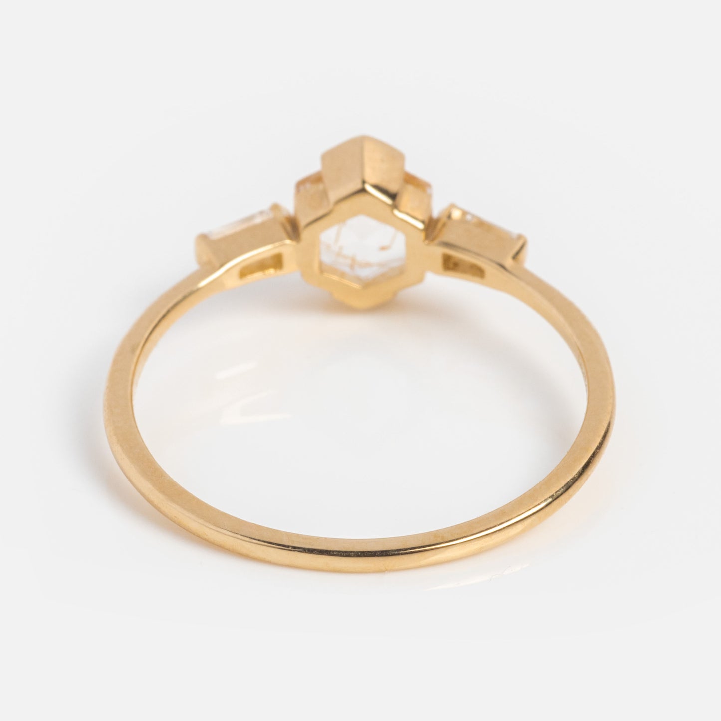 The Solid Gold Rutilated Quartz Illumination Ring features a geometric hexagonal rutilated quartz center and two rectangular side stones, shown on a white background.