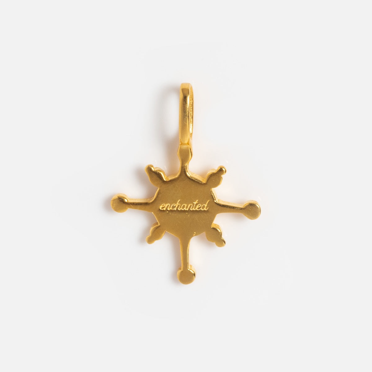 A gold vermeil six-pointed starburst pendant with rounded tips and enchanted engraved at the center from Charms by Hunt of Hounds, photographed on a white background—a charming collectible.
