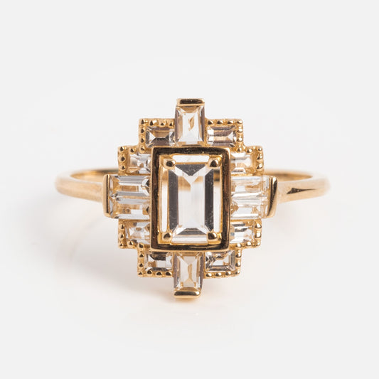 The 14k Vintage Inspired Art Deco Shield Ring showcases a rectangular central clear gemstone, accented by smaller rectangular and square stones in a geometric shield design, displayed on a plain white background.