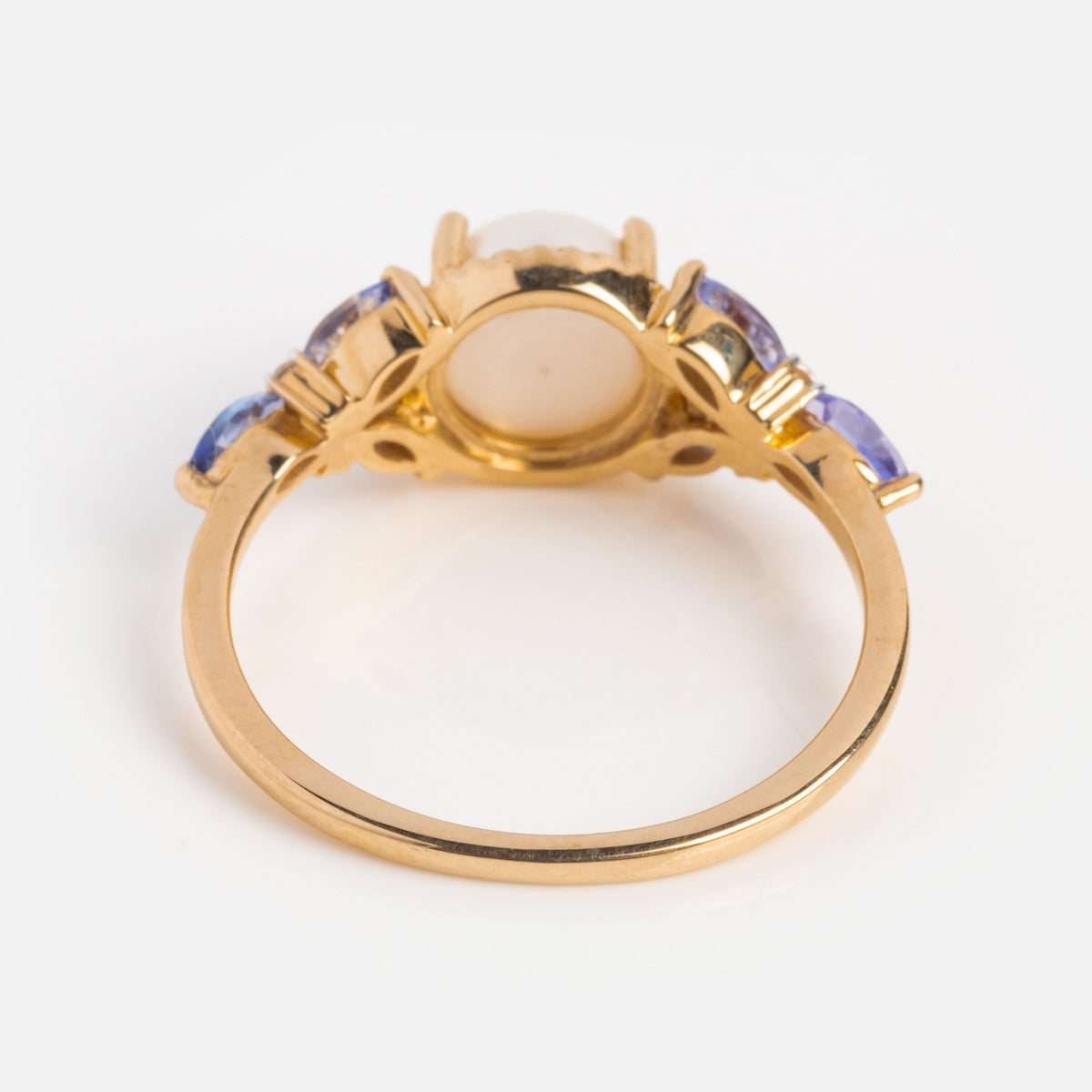 The 14k Vintage Inspired Pearl and Tanzanite Statement Ring showcases a central round pearl, flanked by two smaller tanzanites on each side, all set in decorative prongs and viewed from the back.