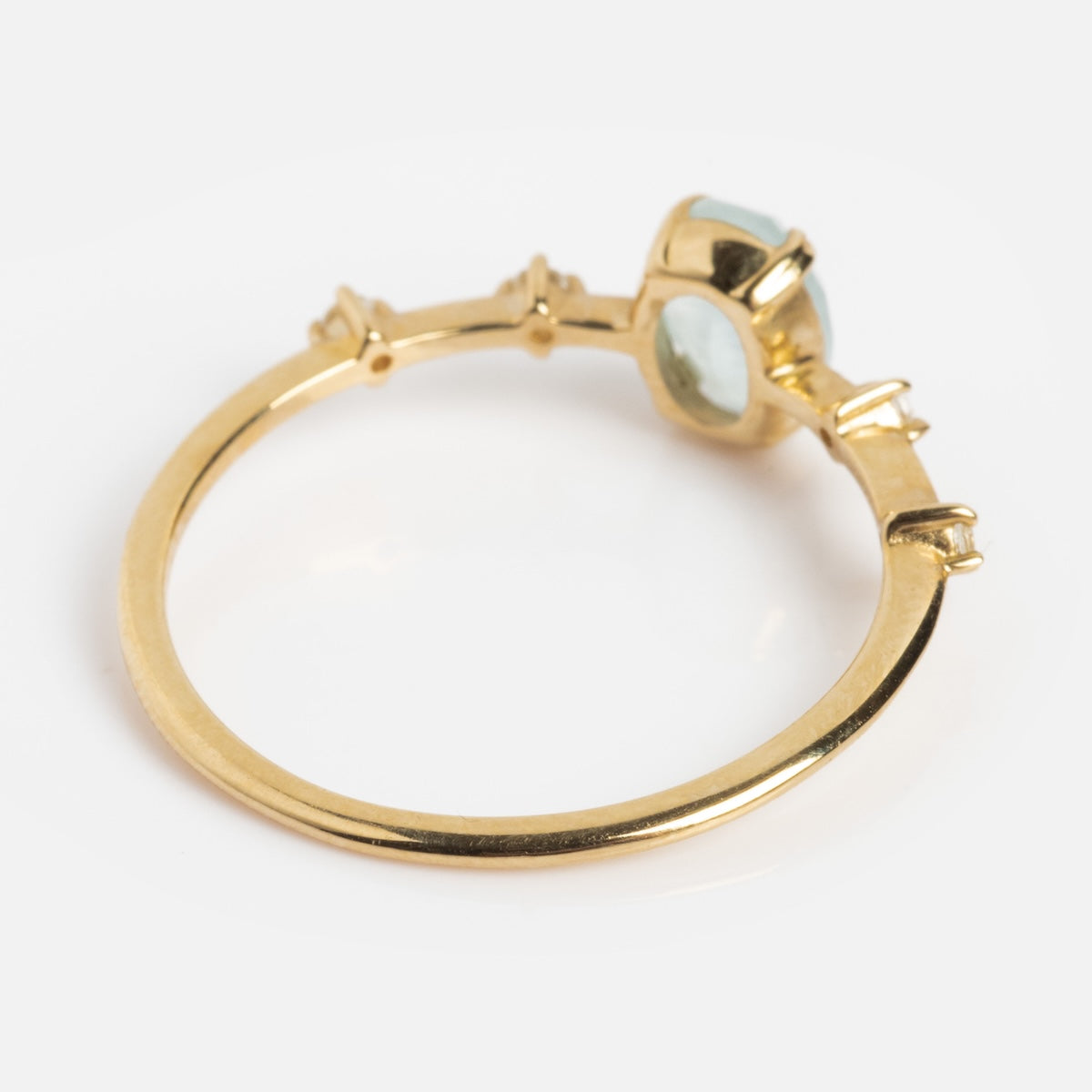 The Solid Gold 2025 March Capsule Classic Aquamarine Statement Ring features a round, light green aquamarine in a bezel setting with gold accents along the band. Shown from the side on a white background, it’s an ideal unique March birthstone ring.