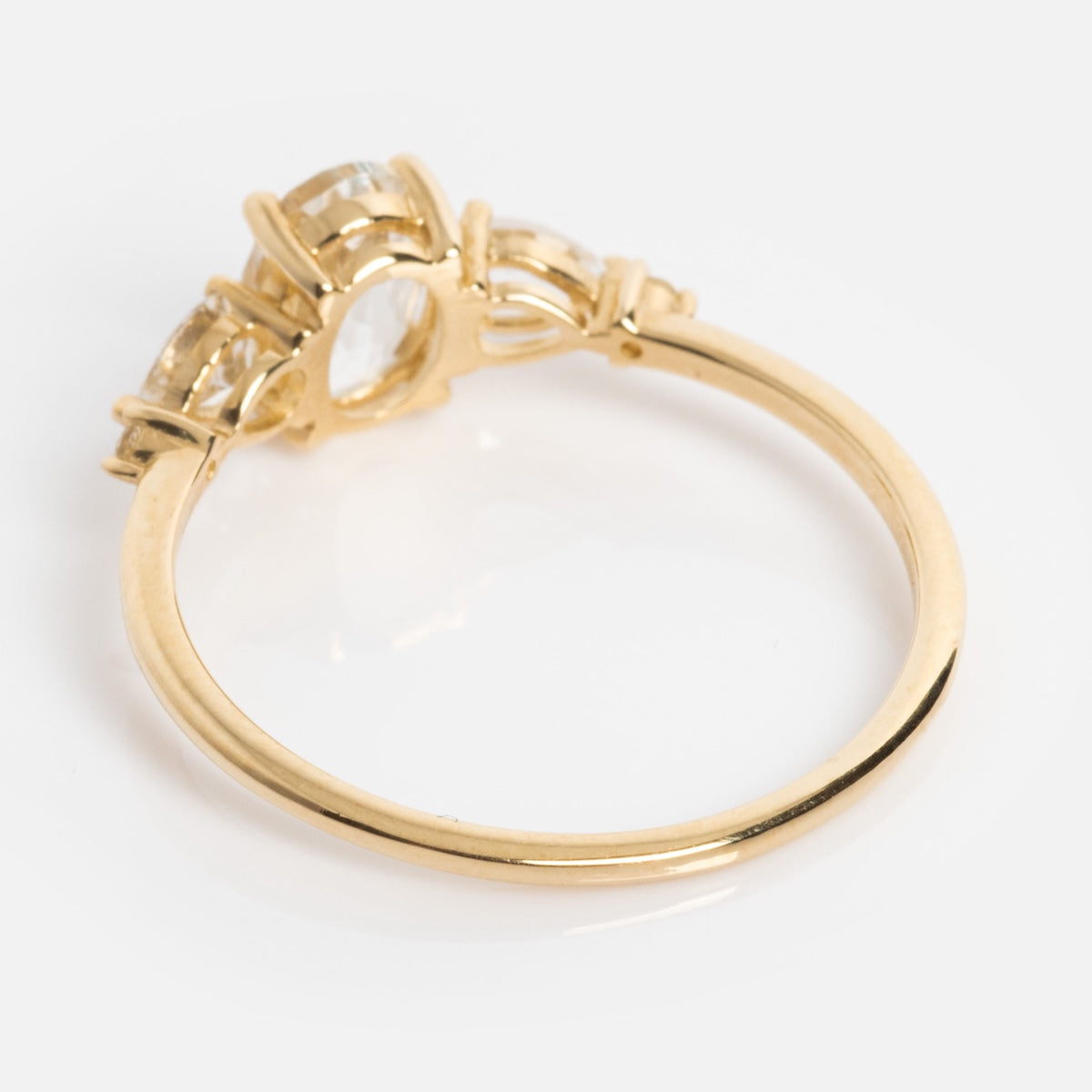 The Solid Gold 2025 April Capsule Classic White Topaz Statement Ring showcases a slim gold band set with three clear white topaz gemstones, making it a refined birthstone jewelry piece, displayed on a white background.