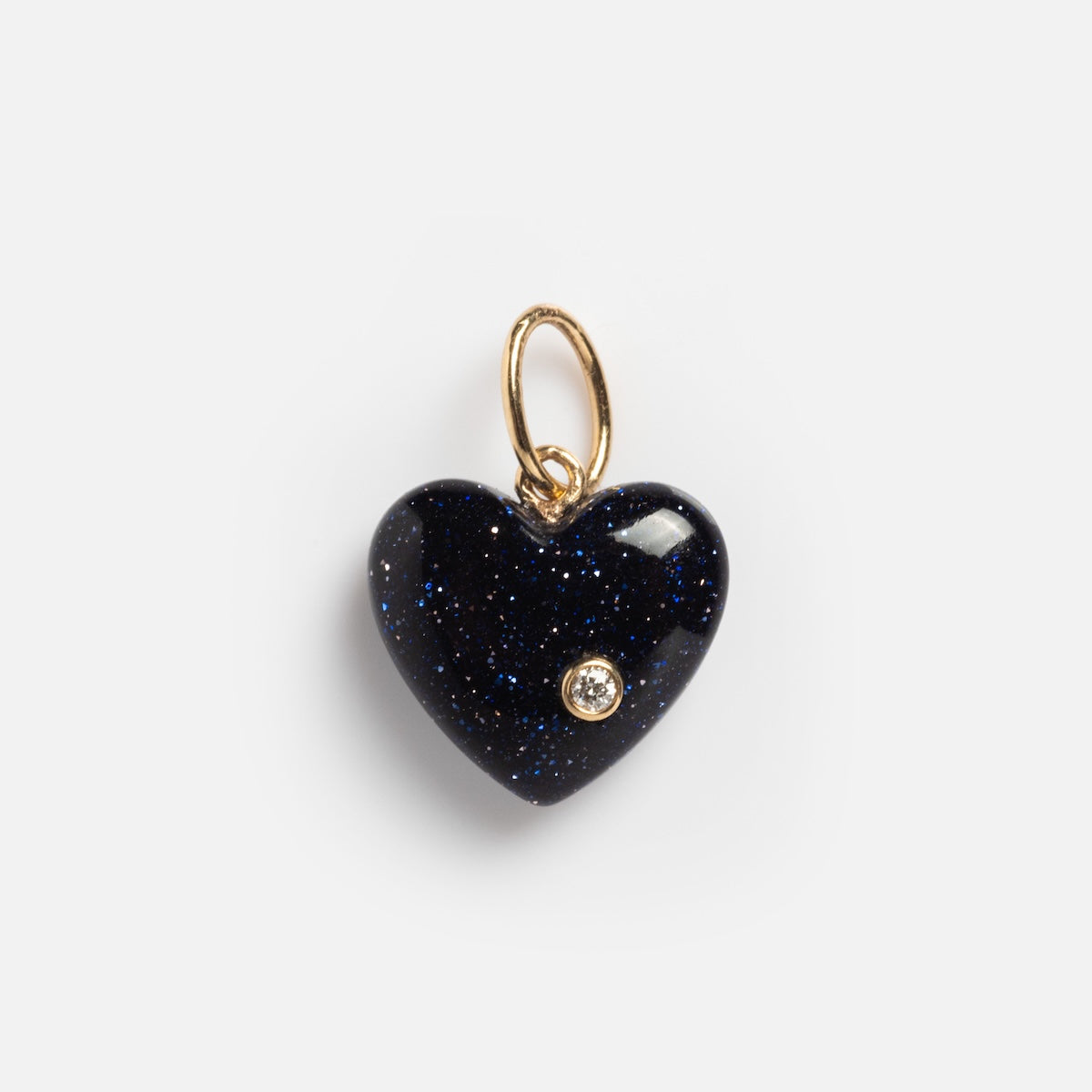 The Solid Gold Full Heart Crystal Charm features a dark blue glittery crystal heart with a small clear gemstone and a gold loop for necklaces, shown on a plain white background.