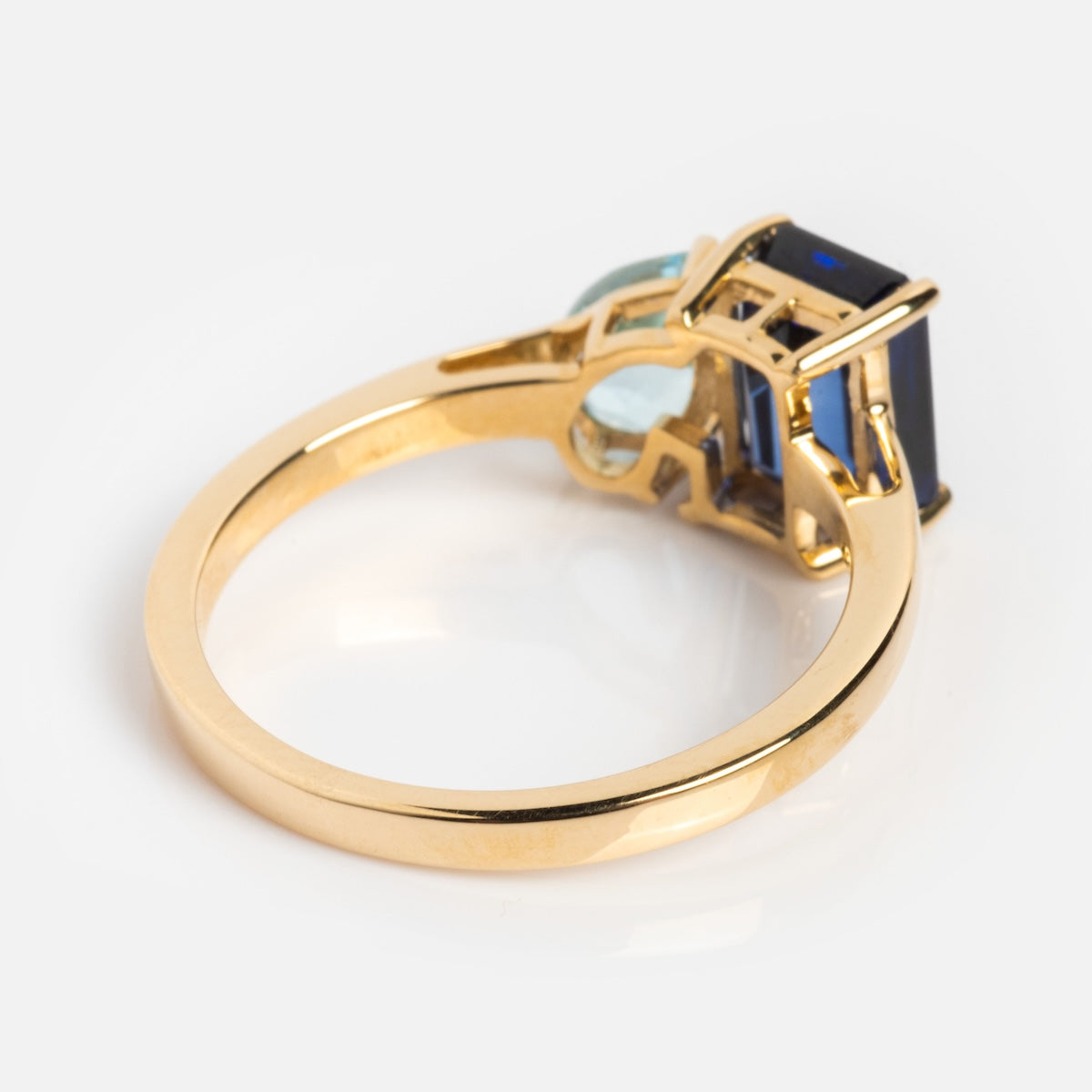 The Solid Gold Toi et Moi Colorful Gemstone Ring showcases a rectangular blue gemstone paired with a smaller oval light blue gem, beautifully presented against a white background.