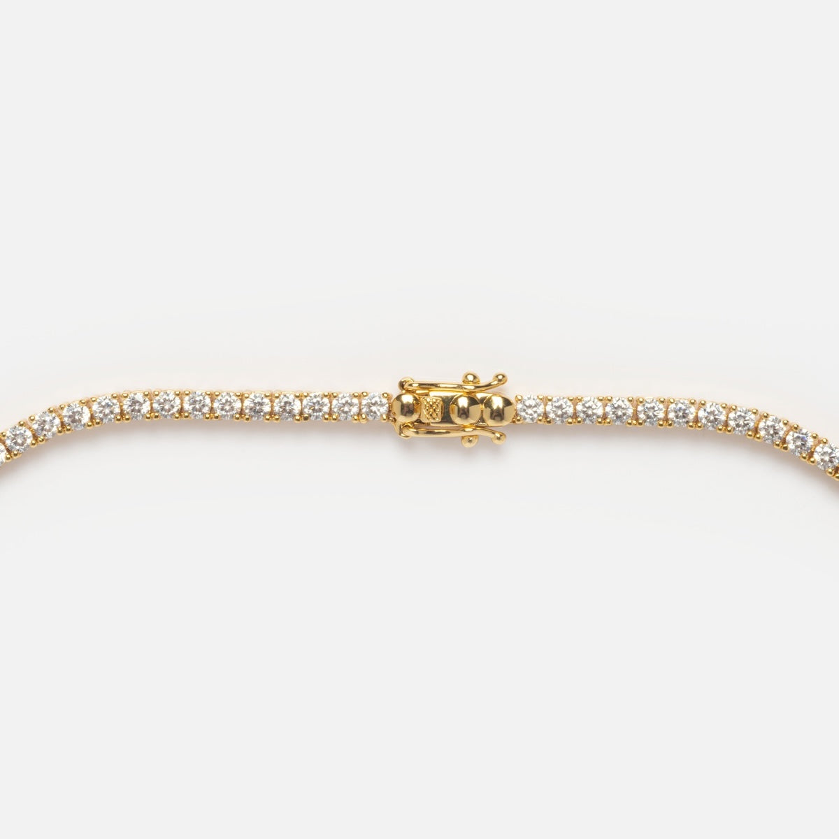 A close-up of a 14k yellow gold plated Tennis Necklace with a row of sparkling white CZ gemstones and a box clasp, displayed on a plain white background.