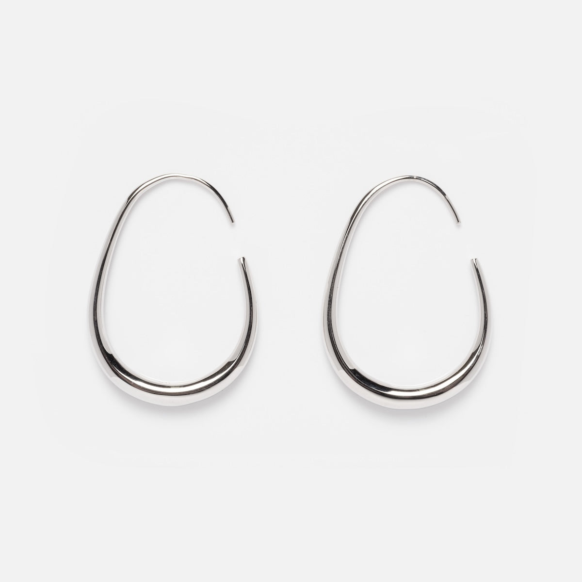 The Fluid Hoop Earrings feature a sleek silver teardrop design, showcased elegantly against a clean white background.